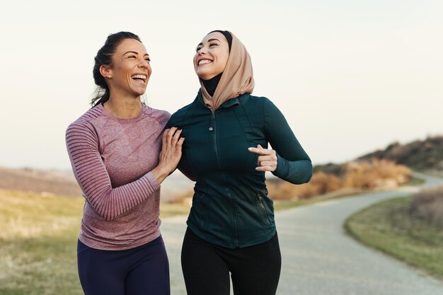Heureuses femmes athlétiques s'amusant en faisant du jogging le matin dans la nature