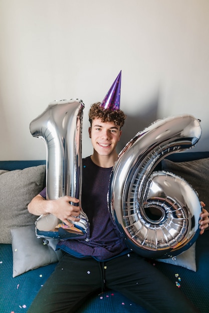 Heureux adolescent tenant des ballons d'anniversaire