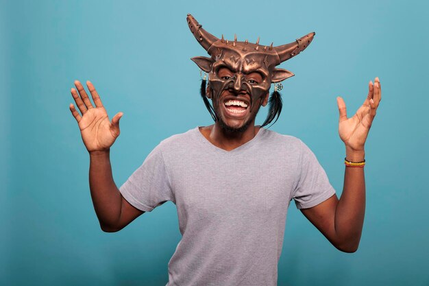 Heureux adulte portant un masque de cérémonie indigène tribal utilisé dans la culture et l'histoire indigènes pour créer un ancien rituel. Homme afro-américain avec objet chaman traditionnel et culturel.