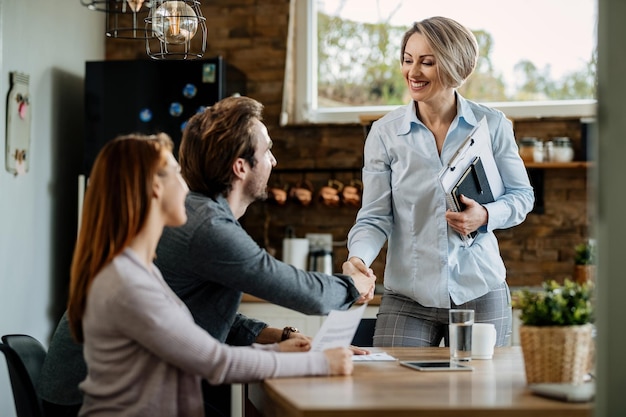 Heureux Agent D'assurance Rencontrant Un Jeune Couple Et Serrant La Main D'un Homme à Leur Domicile