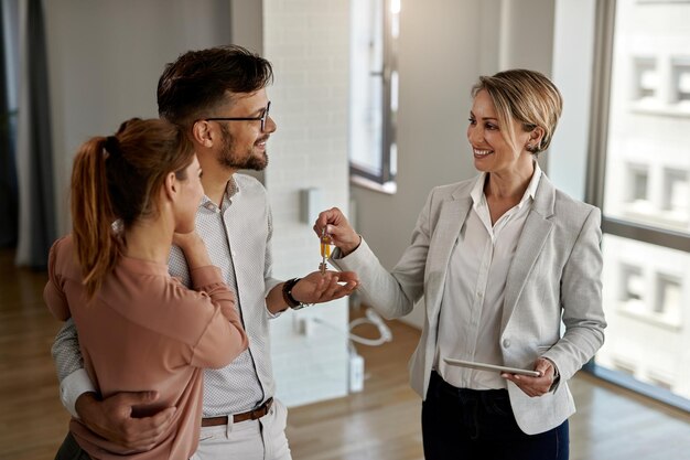 Heureux agent immobilier donnant les clés à un couple qui achète sa nouvelle maison