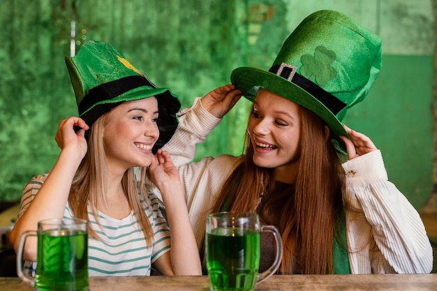 Photo gratuite heureux amies célébrant st. patrick's day ensemble au bar