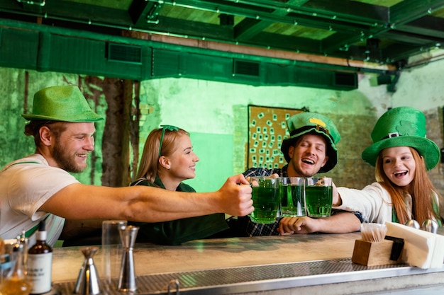 Photo gratuite heureux amis célébrant st. la journée de patrick avec un verre au bar