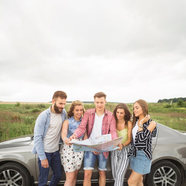 Heureux amis debout près de la voiture à la recherche sur la carte