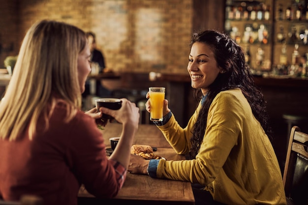Heureux amis féminins appréciant tout en parlant dans un pub