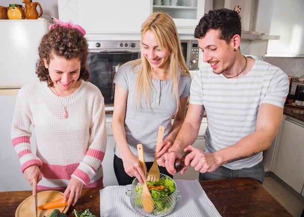 Heureux amis préparant la salade dans la cuisine