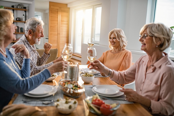 Photo gratuit heureux amis seniors en train de déjeuner ensemble et de griller avec du vin à la table à manger