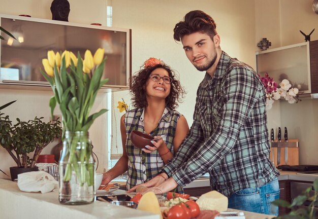 Heureux beau jeune couple cuisiner dans la cuisine à la maison.