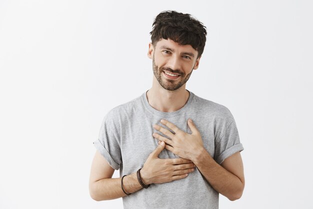 Heureux beau mec posant contre le mur blanc