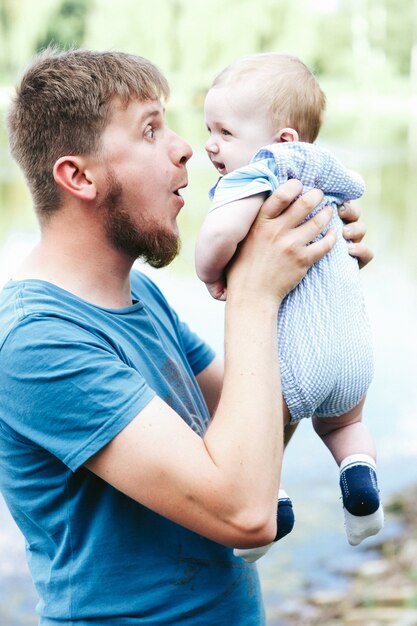 Heureux beau papa, père tenant bébé garçon en vêtements bleus