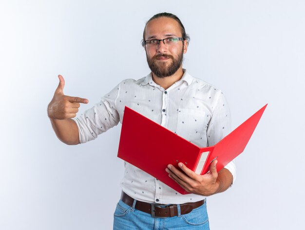 Heureux bel homme adulte portant des lunettes tenant et pointant vers le dossier ouvert