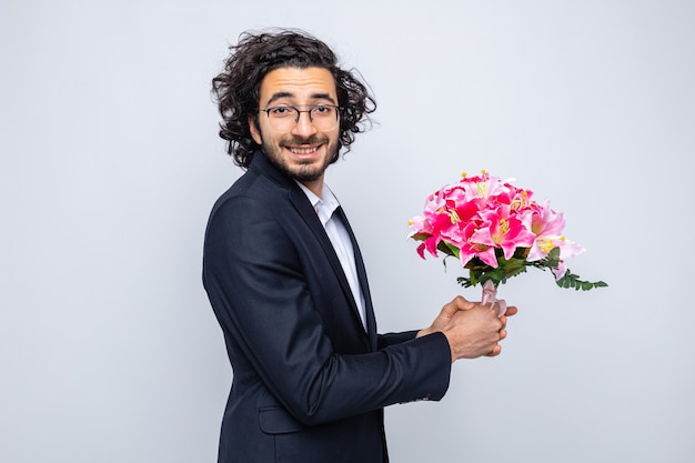Heureux bel homme en costume avec bouquet de fleurs à sourire gaiement