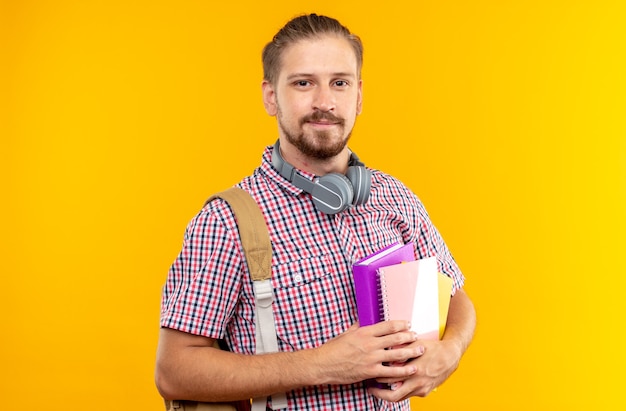 Heureux à la caméra étudiant jeune homme portant un sac à dos tenant un livre