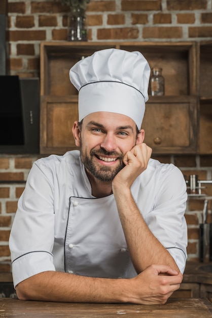 Photo gratuite heureux chef masculin professionnel en regardant la caméra