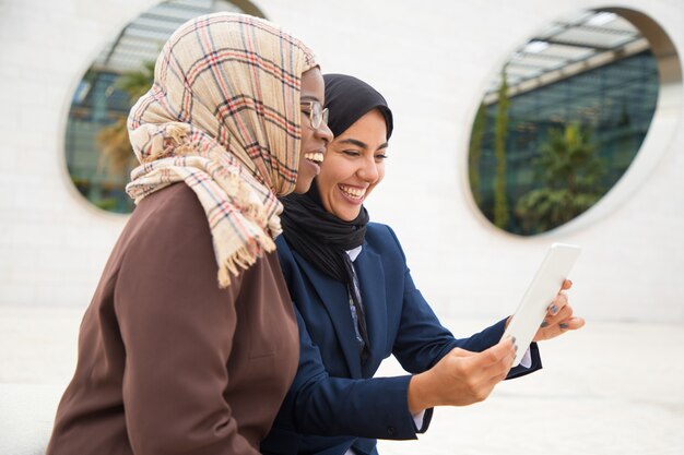 Heureux collègues féminines à l'aide d'une tablette pour un appel vidéo