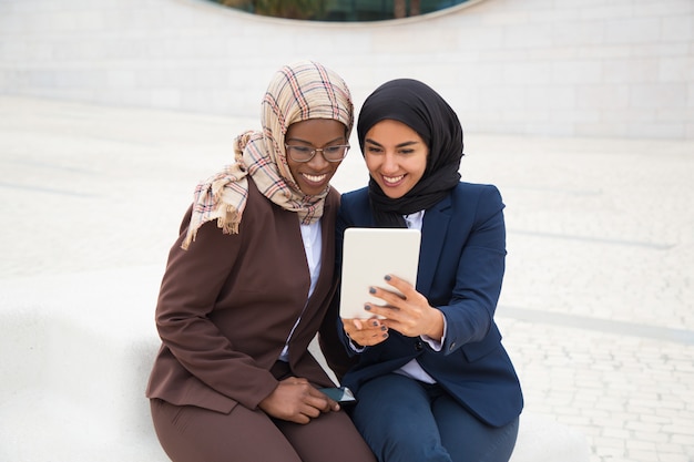 Photo gratuite heureux collègues de travail regarder du contenu sur une tablette