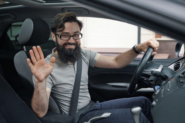 Heureux conducteur de voiture avec ceinture de sécurité bouclée en agitant