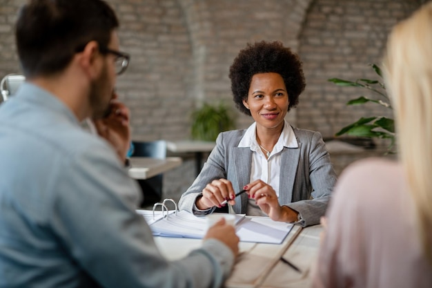 Heureux conseiller financier afro-américain ayant une réunion avec un couple au bureau