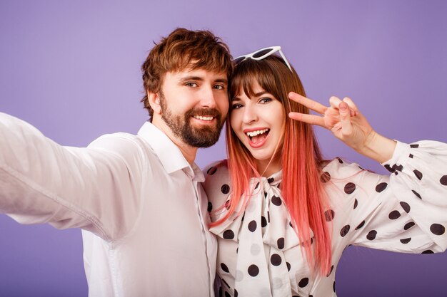 Heureux couple amoureux faisant autoportrait sur mur violet