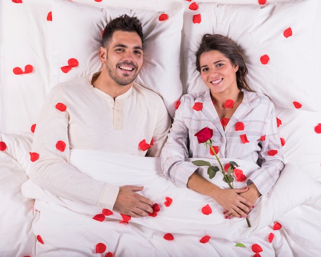 Photo gratuite heureux couple au lit avec des pétales de rose