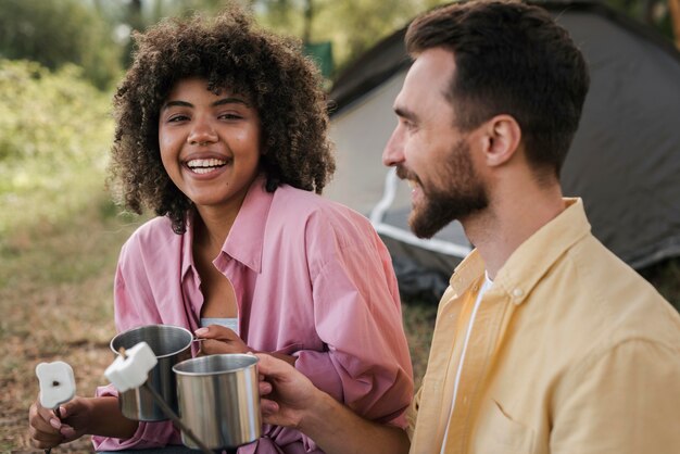 Heureux couple ayant des guimauves en camping