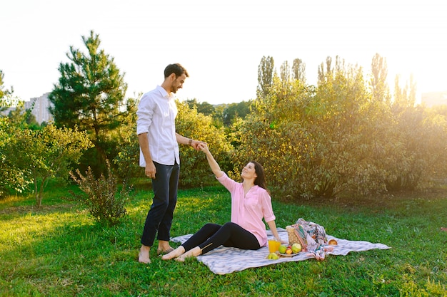 Heureux couple enceinte dans le parc sur picnik