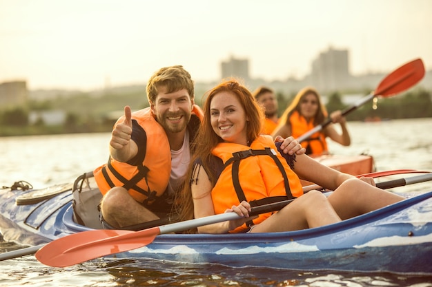 Heureux couple kayak sur la rivière avec coucher de soleil