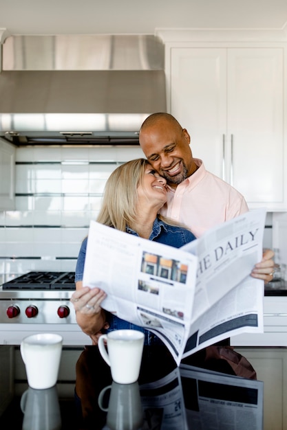 Heureux couple lisant le journal ensemble dans la cuisine