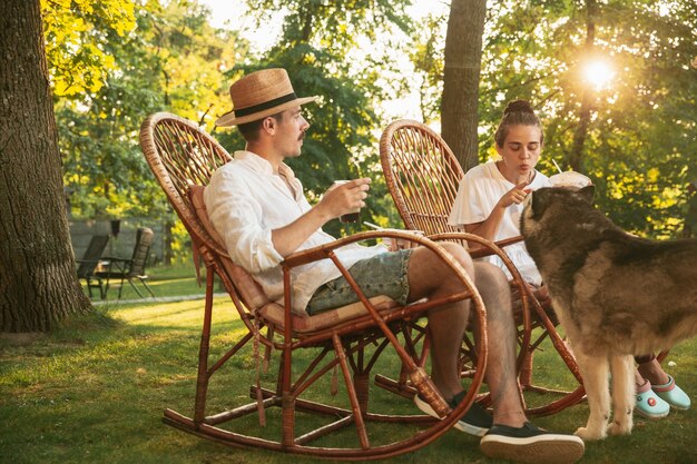 Heureux couple manger et boire des bières au dîner barbecue au coucher du soleil