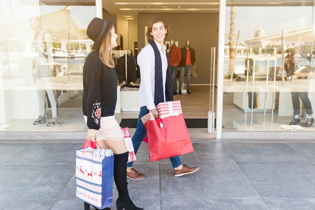 Photo gratuite heureux couple marchant dans la rue avec des sacs