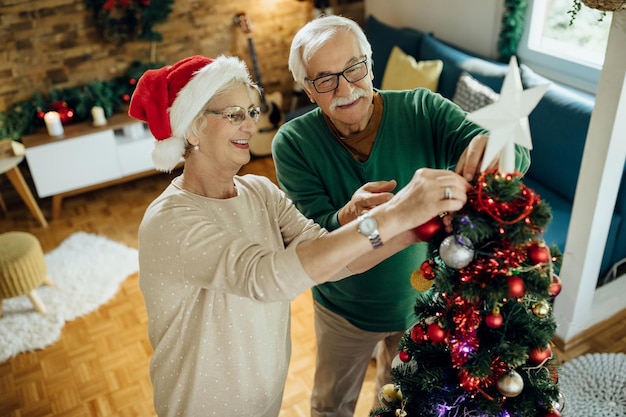 Heureux couple mature se préparant pour Noël et décorant l'arbre à la maison