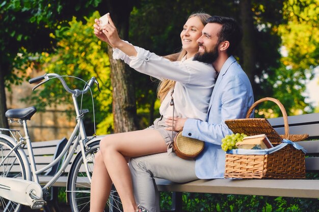 Heureux couple moderne à une date faire selfie dans un parc.