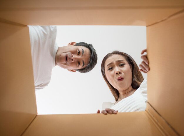 Heureux couple ouvrant une boîte et regardant à l&#39;intérieur du produit