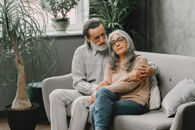 Heureux couple de personnes âgées assis sur un canapé à la maison et parlant. Concept de temps de qualité.