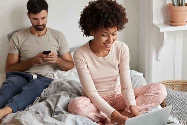 Heureux couple posant à la maison dans leur lit