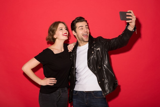 Heureux couple punk posant et faisant selfie sur smartphone
