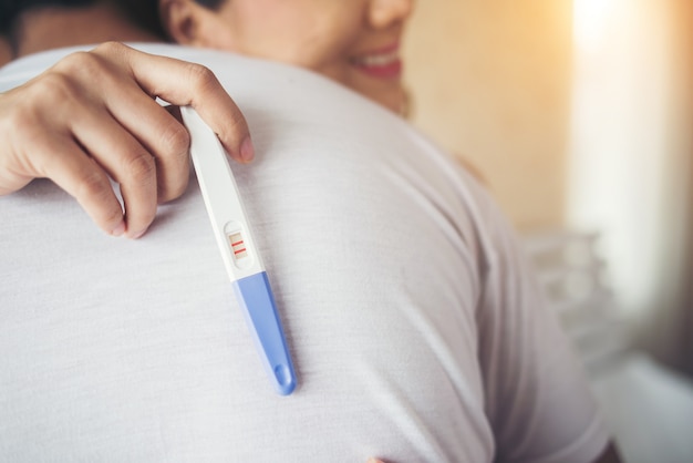 Heureux couple souriant après avoir découvert un test de grossesse positif dans la chambre