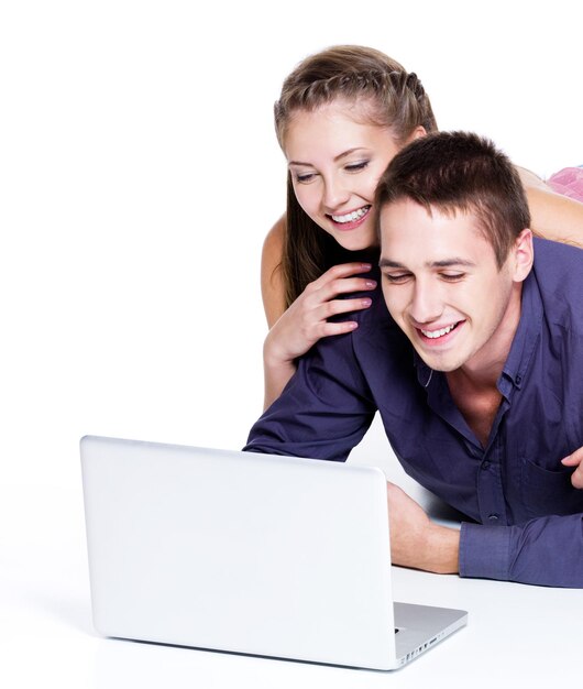 Heureux couple souriant regardant ordinateur portable avec intérêt - isolé sur blanc