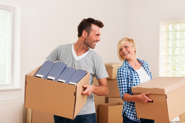 Heureux couple transportant des boîtes en carton dans un nouvel appartement