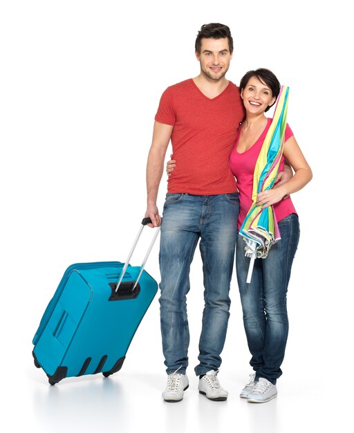 Heureux couple avec valise va voyager, debout au studio sur fond blanc