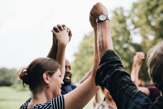 Heureux diverses personnes se tenant la main dans le parc