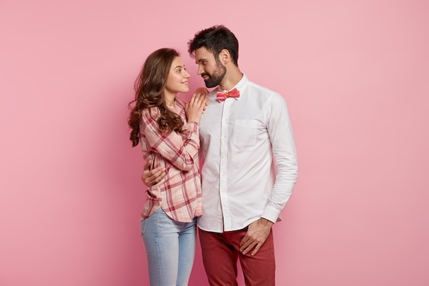 Heureux doux couple amoureux câlins et se regardent avec un sourire doux, vêtus de vêtements élégants et élégants