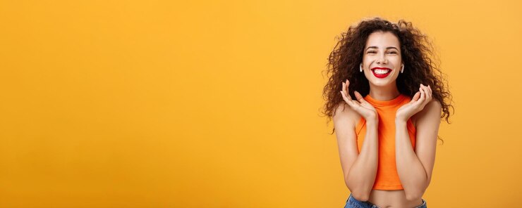 Photo gratuit heureux élégant femme urbaine attrayante avec une coiffure frisée et un anneau dans le nez tout sourire se sentant del