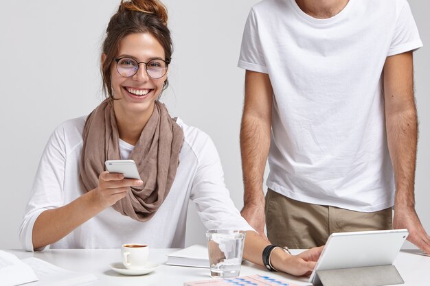 Heureux employé de bureau féminin avec sourire travaille avec un collègue