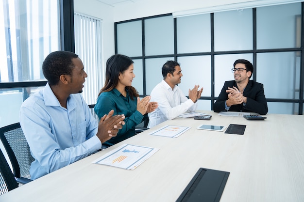 Heureux employés multiethniques applaudissant à la réunion tout en félicitant les uns les autres