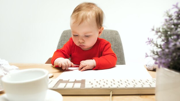 Heureux enfant bébé fille enfant assis avec le clavier de l'ordinateur isolé sur un blanc