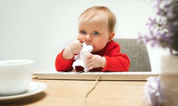 Heureux enfant bébé fille enfant en bas âge assis avec clavier d'ordinateur isolé