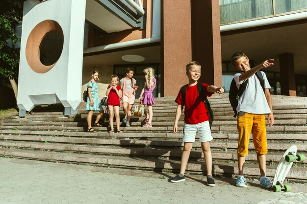 Heureux les enfants jouant dans la rue de la ville en journée d'été ensoleillée devant un bâtiment moderne