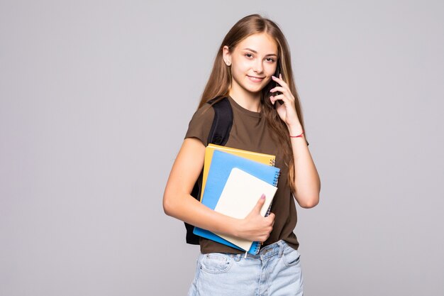 Heureux étudiant femme souriante parlant au téléphone isolé sur un mur blanc