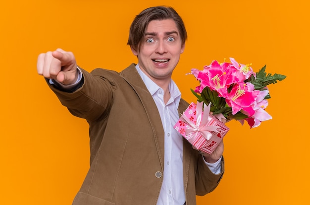 Heureux et excité jeune homme tenant un bouquet de fleurs pointant